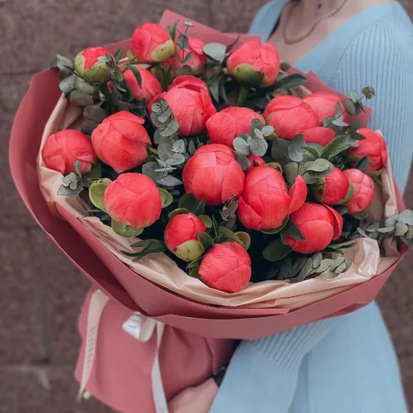 Букет из 19 коралловых пионов с эвкалиптом в розово-персиковой упаковке