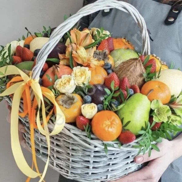 Плетёная светлая корзина с мандаринами, клубникой, грушами, кокосом и кремовыми розами