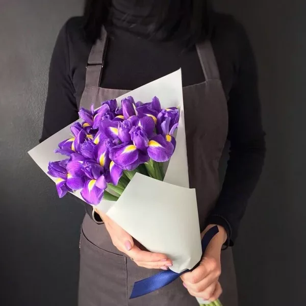 Монобукет из 15 фиолетовых ирисов в белой бумажной упаковке с синей атласной лентой