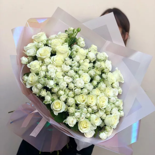 Пышный букет из белых кустовых и одноголовых роз в светлой перламутровой упаковке