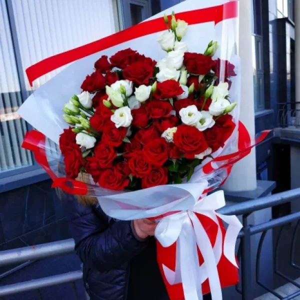 Объёмный букет из красных кустовых роз и белой эустомы в красно-белой упаковке с атласной лентой