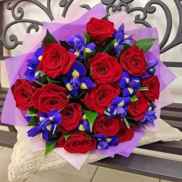 Сборный букет из красных роз и синих ирисов в сиреневой упаковке
