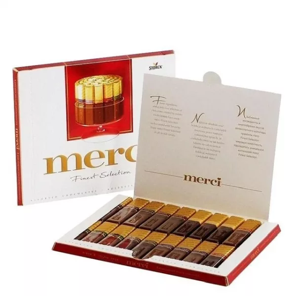 Открытая коробка конфет Merci Finest Selection с рядами шоколадных конфет в золотой обёртке