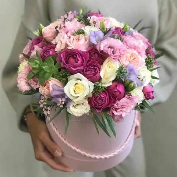 Шляпная коробка розового цвета с куполом из малиновых кустовых роз, кремовых роз, розовых эустом и сиреневой фрезии