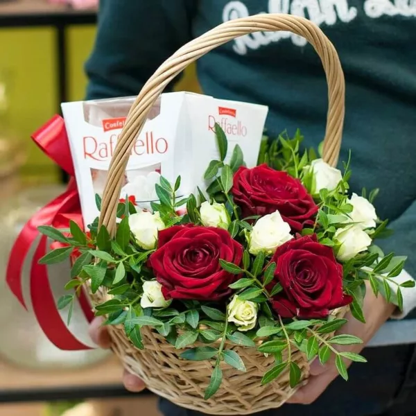 Плетёная корзина с красными розами, белой кустовой розой, писташем и Raffaello