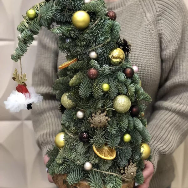 Новогодняя ёлочка из живой хвои с золотыми шарами, шишками и апельсином на деревянном срубе