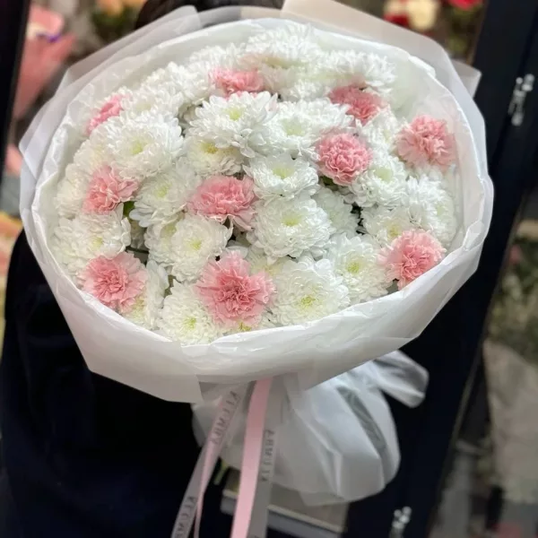 Пышный букет из белых кустовых хризантем с розовыми диантусами в белой упаковке