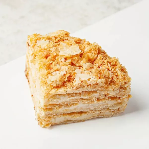 Кусок торта «Наполеон» с хрустящей корочкой, слоистыми коржами и кремовой прослойкой