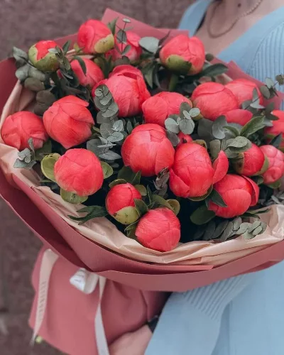 Букет из 19 коралловых пионов с эвкалиптом в розово-персиковой упаковке