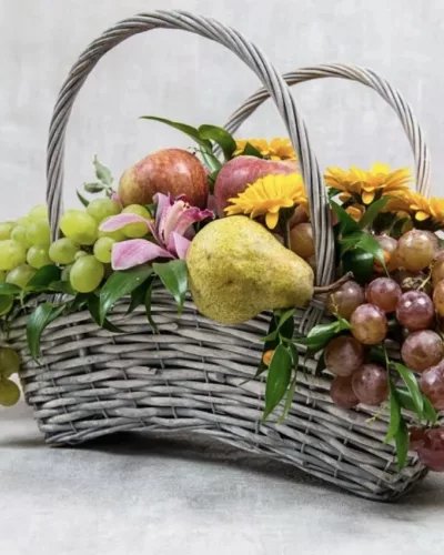 Плетёная корзина с виноградом, грушей, яблоками, жёлтыми герберами и розовой альстромерией