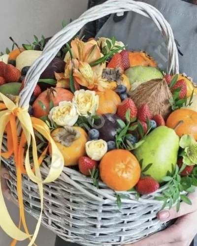 Плетёная светлая корзина с мандаринами, клубникой, грушами, кокосом и кремовыми розами