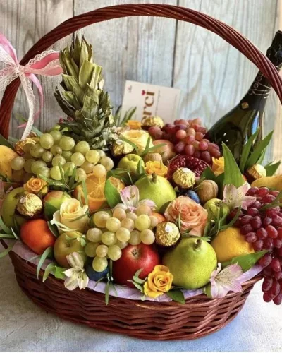 Плетёная корзина с фруктами, персиковыми розами, виноградом и шампанским