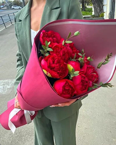 Букет из 11 малиновых пионов с эвкалиптом в малиновой бумажной упаковке с белой лентой