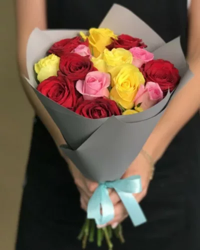 Букет из 15 разноцветных роз — красные, жёлтые, розовые — в серой упаковке с голубой лентой