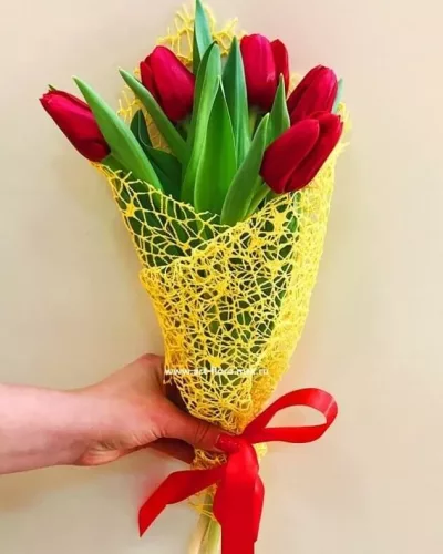 Монобукет из 7 красных тюльпанов в жёлтой сетчатой упаковке с красной атласной лентой