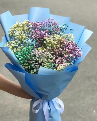 Букет из 9 радужных гипсофил — жёлтые, розовые, голубые и зелёные соцветия в голубой упаковке с белой лентой