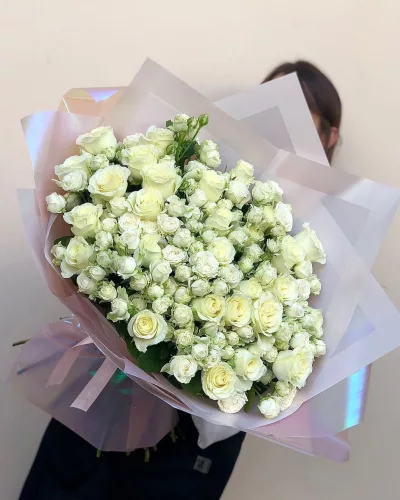 Пышный букет из белых кустовых и одноголовых роз в светлой перламутровой упаковке