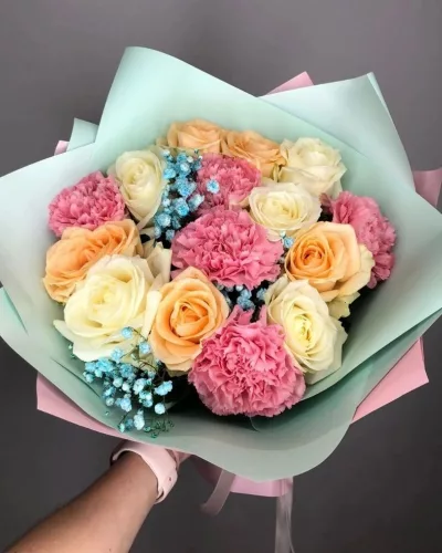 Сборный букет с персиковыми и кремовыми розами, розовыми гвоздиками и голубой гипсофилой в мятно-розовой упаковке