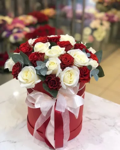 Круглая красная коробка с куполом из красных и белых роз, эвкалипт, белый бант